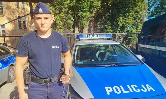 Policjant stoi przy radiowozie