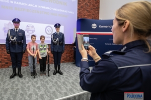 Policjanta robi zdjęcia pamiątkowe laureatom gali finałowej konkursu plastyczno-filmowego pn. Artystyczny przeWODNIK