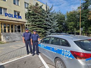 Policjanci stojący przy radiowozie na tle Komendy Powiatowej Policji w Pabianicach