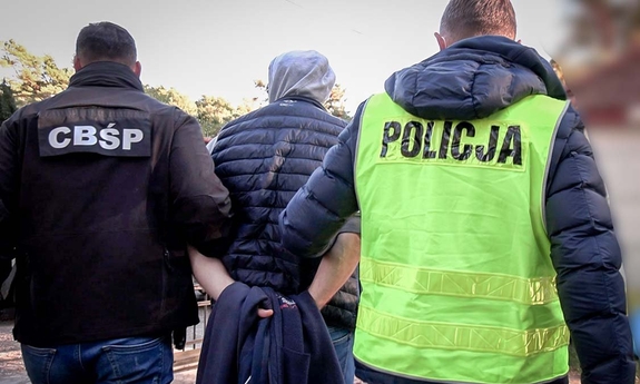 dwaj policjanci prowadzą zatrzymanego mężczyznę