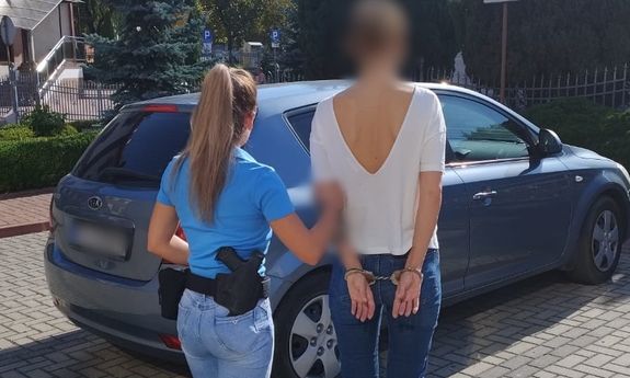 Policjantka prowadzi zatrzymaną do nieoznakowanego radiowozu