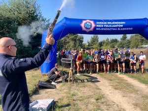 linia startu, zawodnicy ustawieni przed linią, po lewej stronie stoi policjant w mundurze, daje sygnał do startu