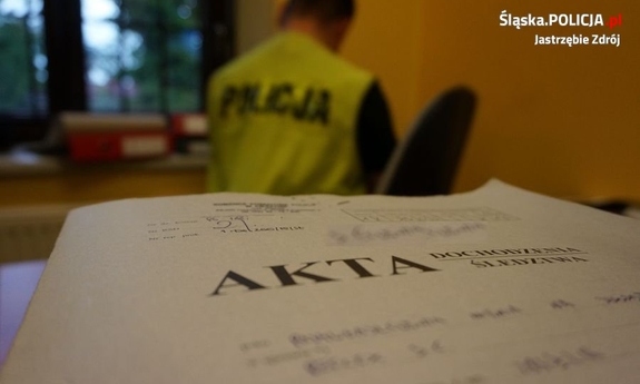 zdjęcie teczki, w tle siedzi policjant