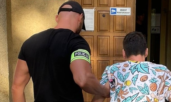 nieumundurowany policjant prowadzi osobę zatrzymaną do budynku prokuratury
