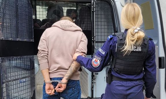 Policjantka prowadzi zatrzymanego do radiowozu