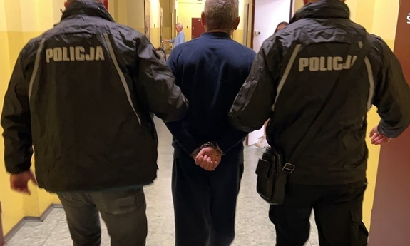 dwóch policjantów prowadzi zatrzymanego podejrzanego o zabójstwo