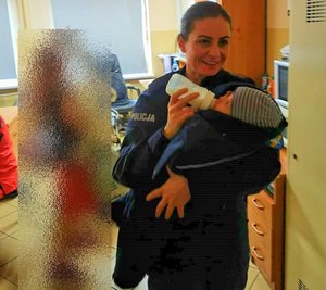 policjantka karmiąca butelką noworodka owiniętego w policyjna bluzę