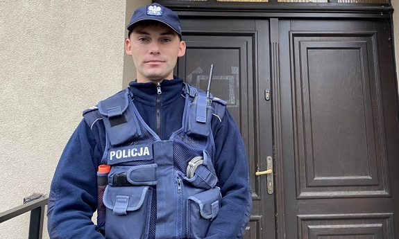 sierżant Roch przed drzwiami, nad którymi widnieje napis policja