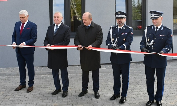 dwaj policjanci i trzej mężczyźni przecinają biało-czerwoną wstęgę
