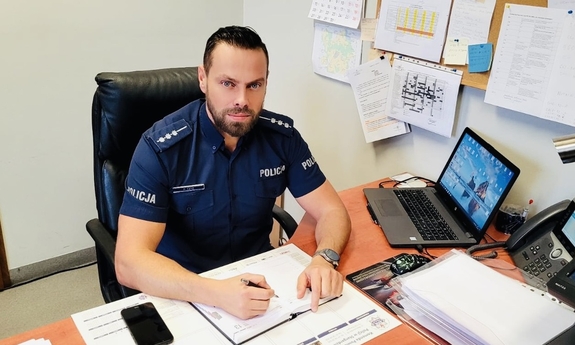 Starszy aspirant Rafał Czyż siedzi przy biurku