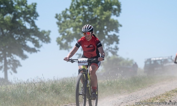 Kobieta w stroju sportowym jedzie na rowerze drogą szutrową