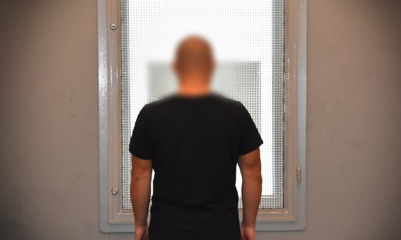 zatrzymany mężczyzna stoi w policyjnym areszcie