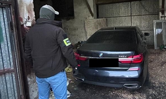 Policjant stoi przy odzyskanym samochodzie