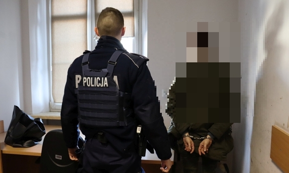 Policjant z zatrzymaną osobą skutą w kajdanki