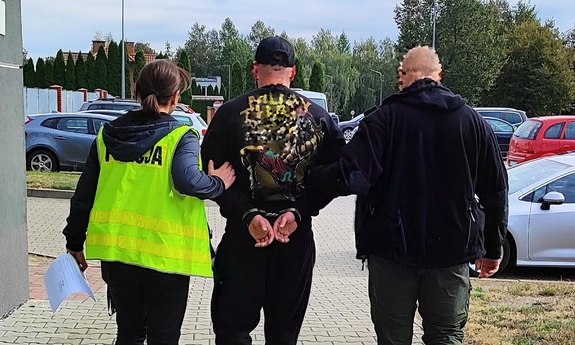 policjant i policjantka prowadza zatrzymanego