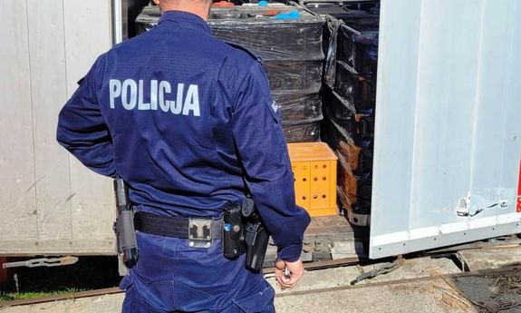 Policjant patrzy na beczki z odpadami