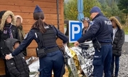 policjanci pomagają uchodźcom okrywając ich kocami ratunkowymi