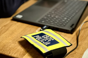 Laptop na biurku, obok opaska z napisem CBZC Policja.