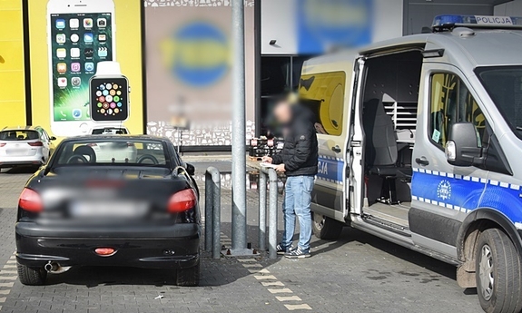 czarny samochód, obok radiowozu policyjnego