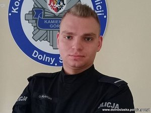 Dzielnicowy w mundurze na tle loga policji Kamiennej Góry