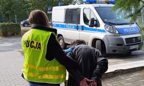 Policjantka prowadzi do radiowozu zatrzymanego mężczyznę