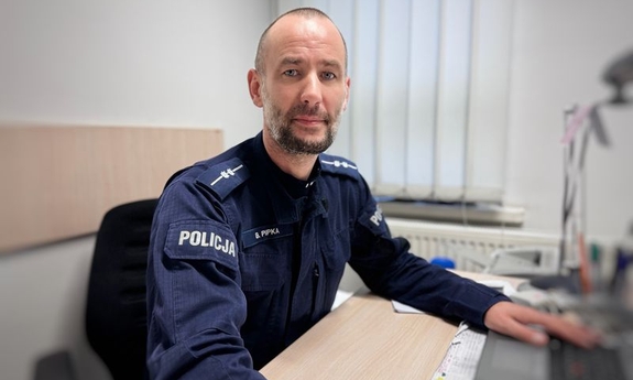 Policjant patrzy w obiektyw siedzi za biurkiem