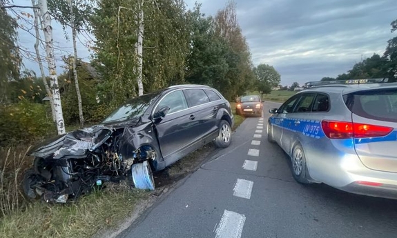 rozbity samochód, który wjechał do rowu obok niego na jezdni stoi oznakowany policyjny radiowóz