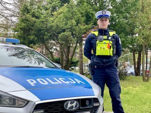 policjant stoi przy radiowozie