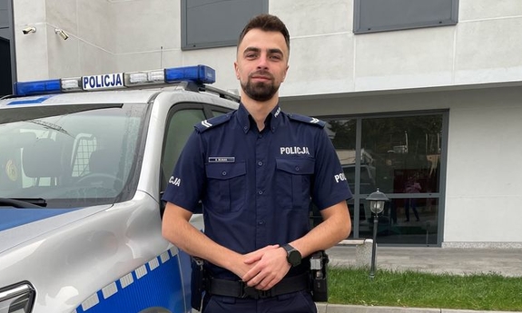 Policjant na tle radiowozu.