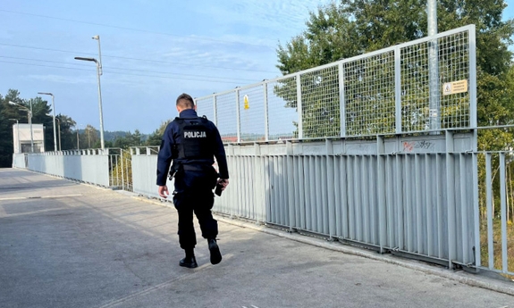 Policjant na kładce dla pieszych przy nad torami