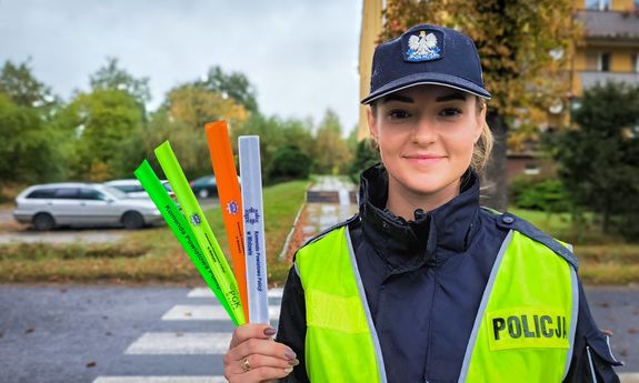 Policjantka trzyma w ręku 4 różnokolorowe odblaski