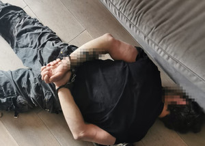 zatrzymany leżący twarzą do podłogi  z założonymi na ręce trzymane z tyłu kajdankami