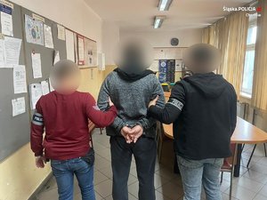 zatrzymany mężczyzna zakuty w kajdanki z dwoma policjantami