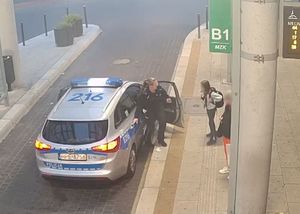 umundurowana policjantka wychodzi z radiowozu, na przystanku autobusowym stoi zaginiona dziewczynka