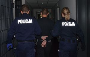 Policjanci prowadzą zatrzymanego