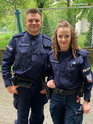 Policjant i policjantka stoją na tle zielonych roślin