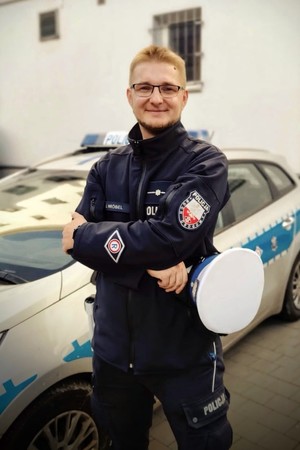 Policjant stoi na tle radiowozu