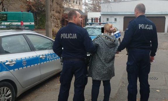 policjanci prowadzą zatrzymaną kobietę