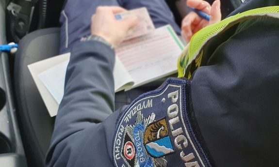Policjant wypisuje mandat. Zbliżenie na jego rękę
