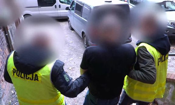 Dwóch policjantów prowadzi zatrzymanego