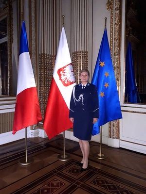 kom. Renata Graf stoi na tle flag Francji, Polski i Unii Europejskiej