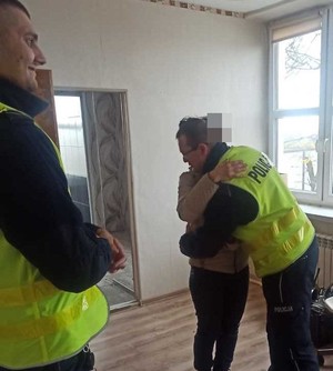 Policjant obejmuje kobietę, stoją w pomieszczeniu, obok drugi policjant