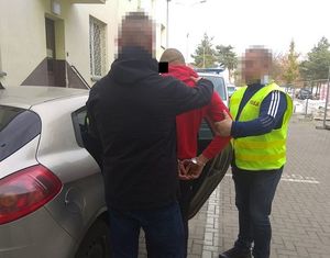 policjanci prowadzą do samochodu zatrzymanego nastolatka