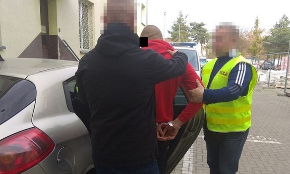 policjanci prowadzą do samochodu zatrzymanego nastolatka
