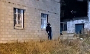 Policjant zaglądający przez okno do niezamieszkałego murowanego domu
