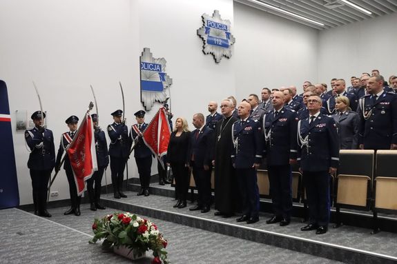 Policjanci stoją na baczność. Po prawej stronie stoi poczet sztandarowy