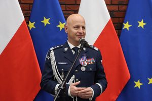 Komendant Główny Policji stoi na tle flag Polski i Unii Europejskiej