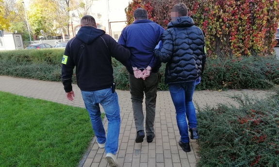 dwaj nieumundurowani policjanci prowadza zatrzymanego