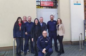 policjanci stoją przed drzwiami budynku komisariatu