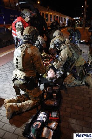Policyjni kontrterroryści udzielają pomocy poszkodowanemu przykrytemu złotem kocem